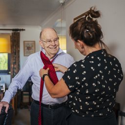 Woman helping an older man put on a tie