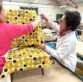 An upcycling charity re-upholstering a chair