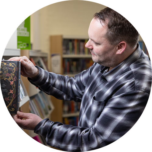 Man taking a book from a library bookshelf