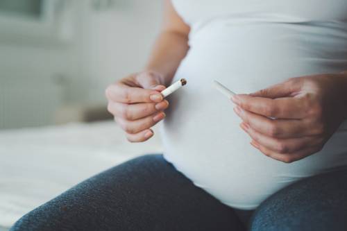 Pregnant woman snapping a cigarette in half.