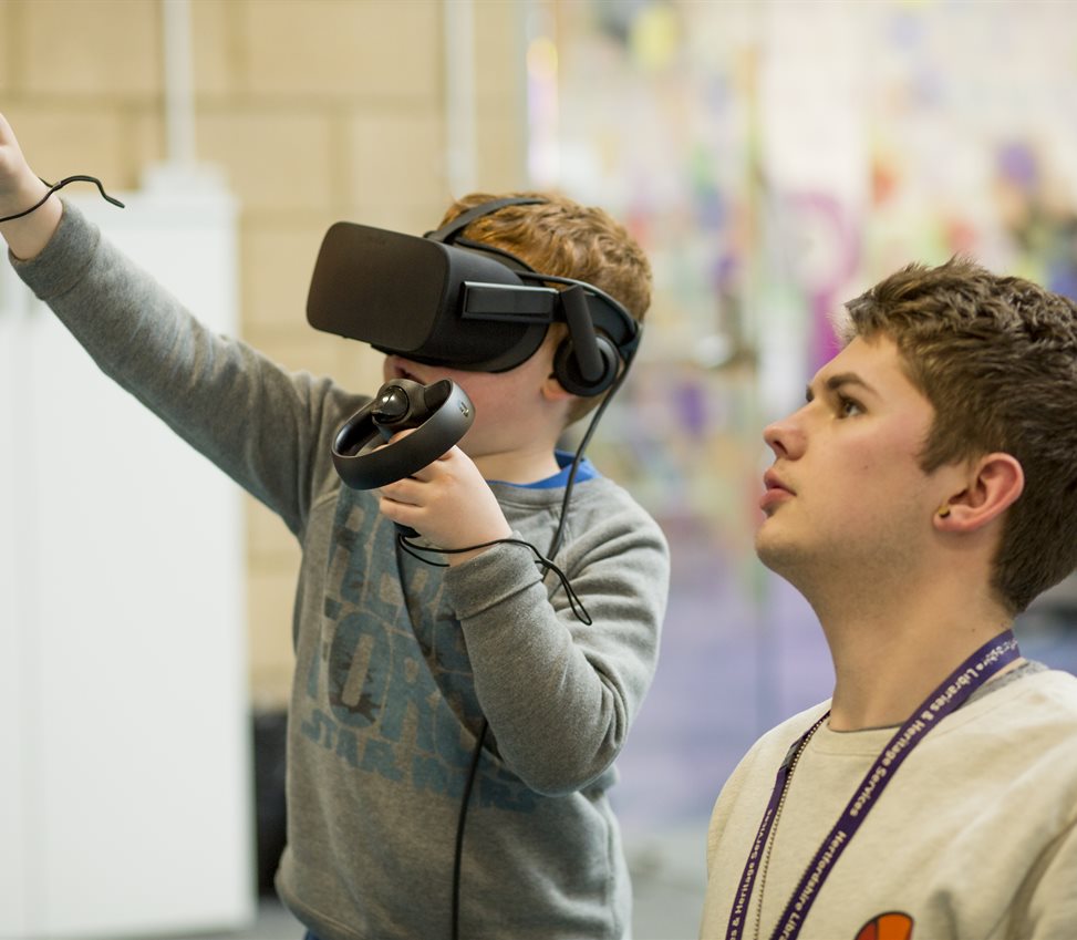 Volunteer helping a boy with a VR headset