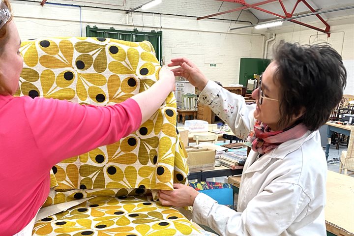 An upcycling charity re-upholstering a chair