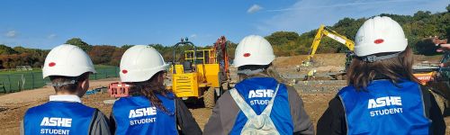 Pupils from the Valley school wearing hi vis and helmets, at the construction site for their new school building.